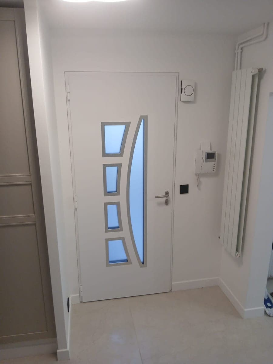 Porte d'entrée blanche à hublots, carrelage et murs blancs sans trace