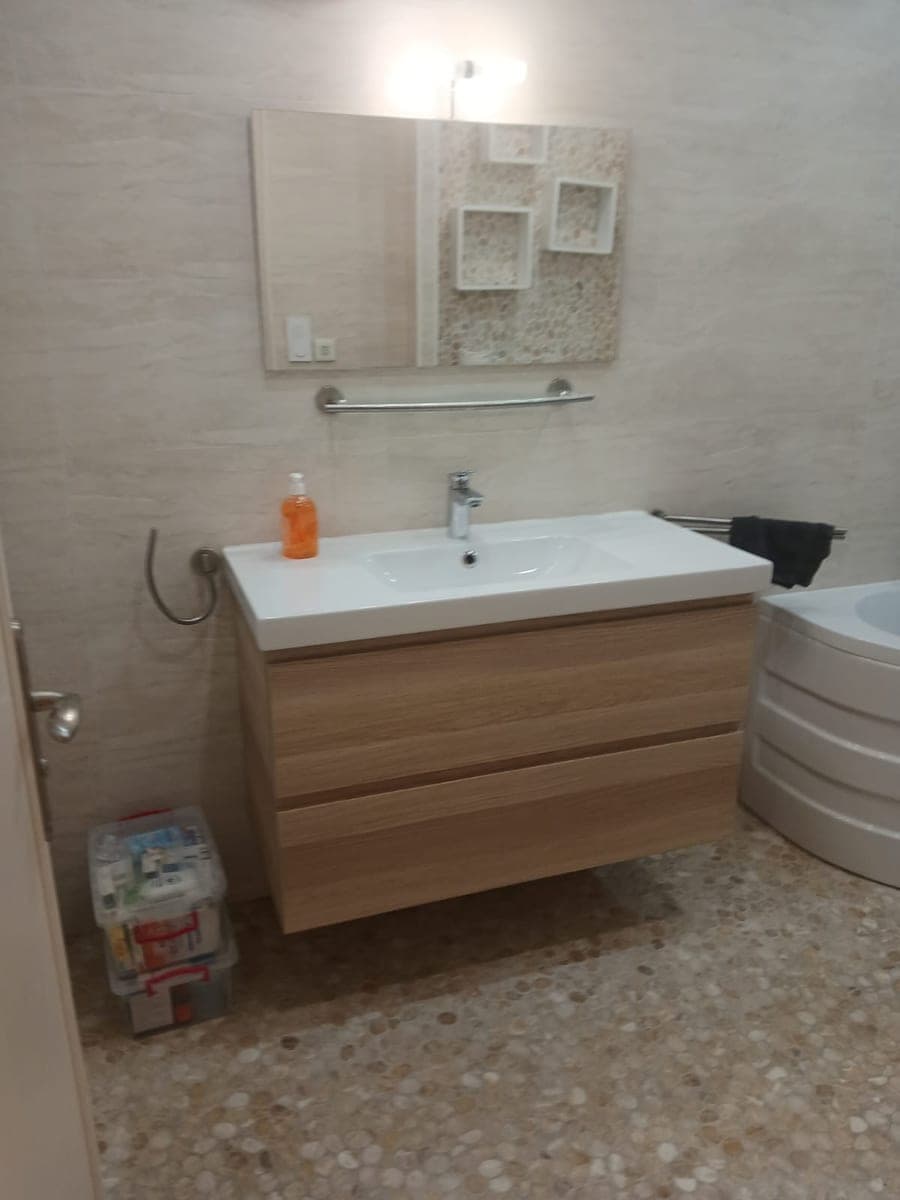 Meuble vasque en bois clair sous un miroir, mur décoré de niches