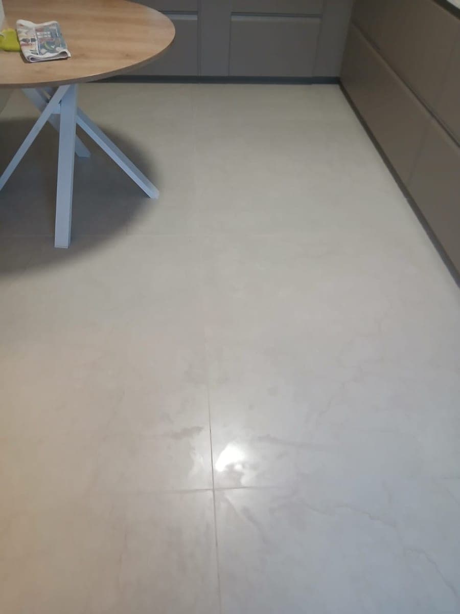 Grand carrelage clair et brillant d'une cuisine, au pied d'une table ronde