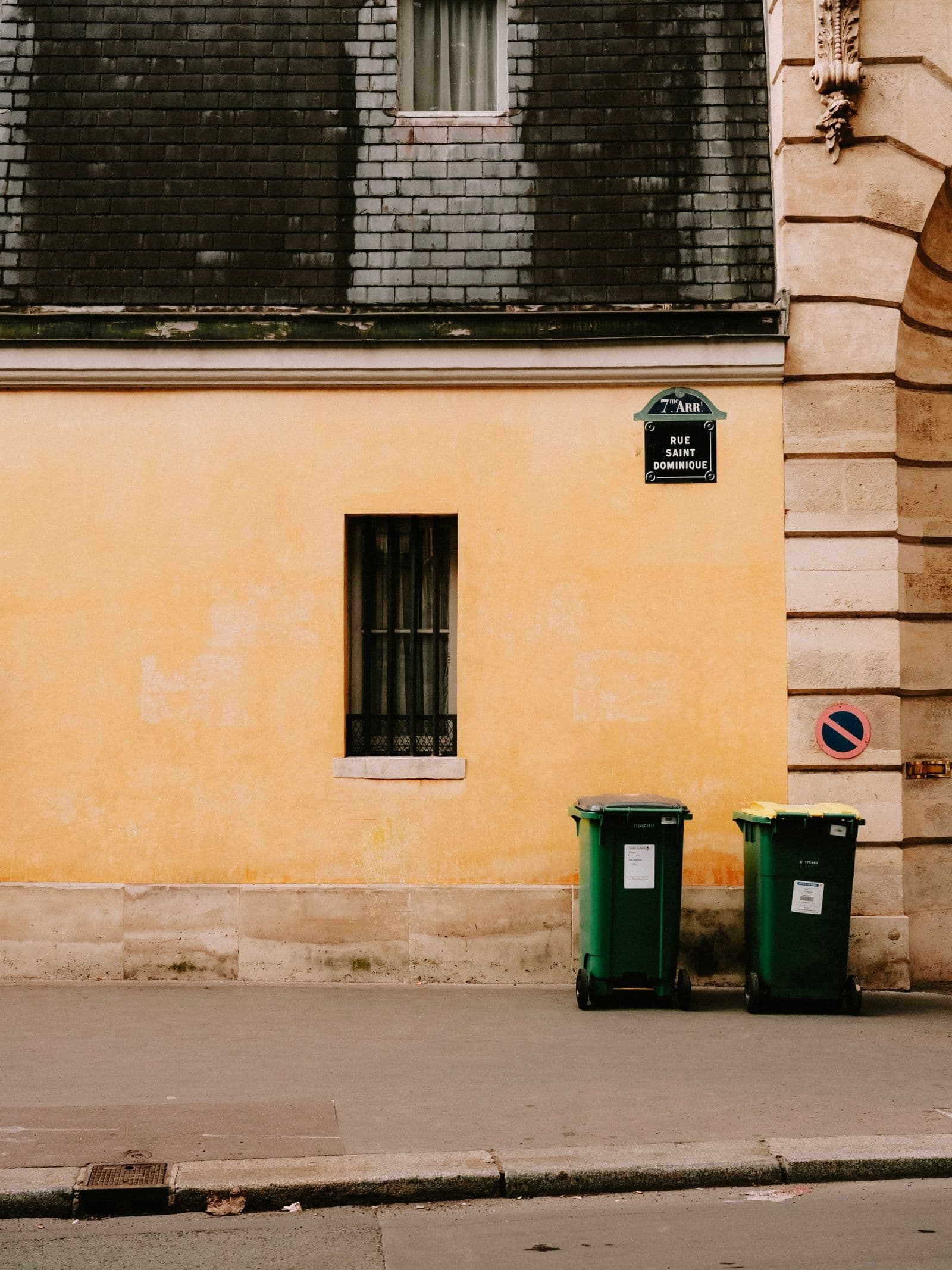 Bacs roulants verts alignés le long d'une rue parisienne