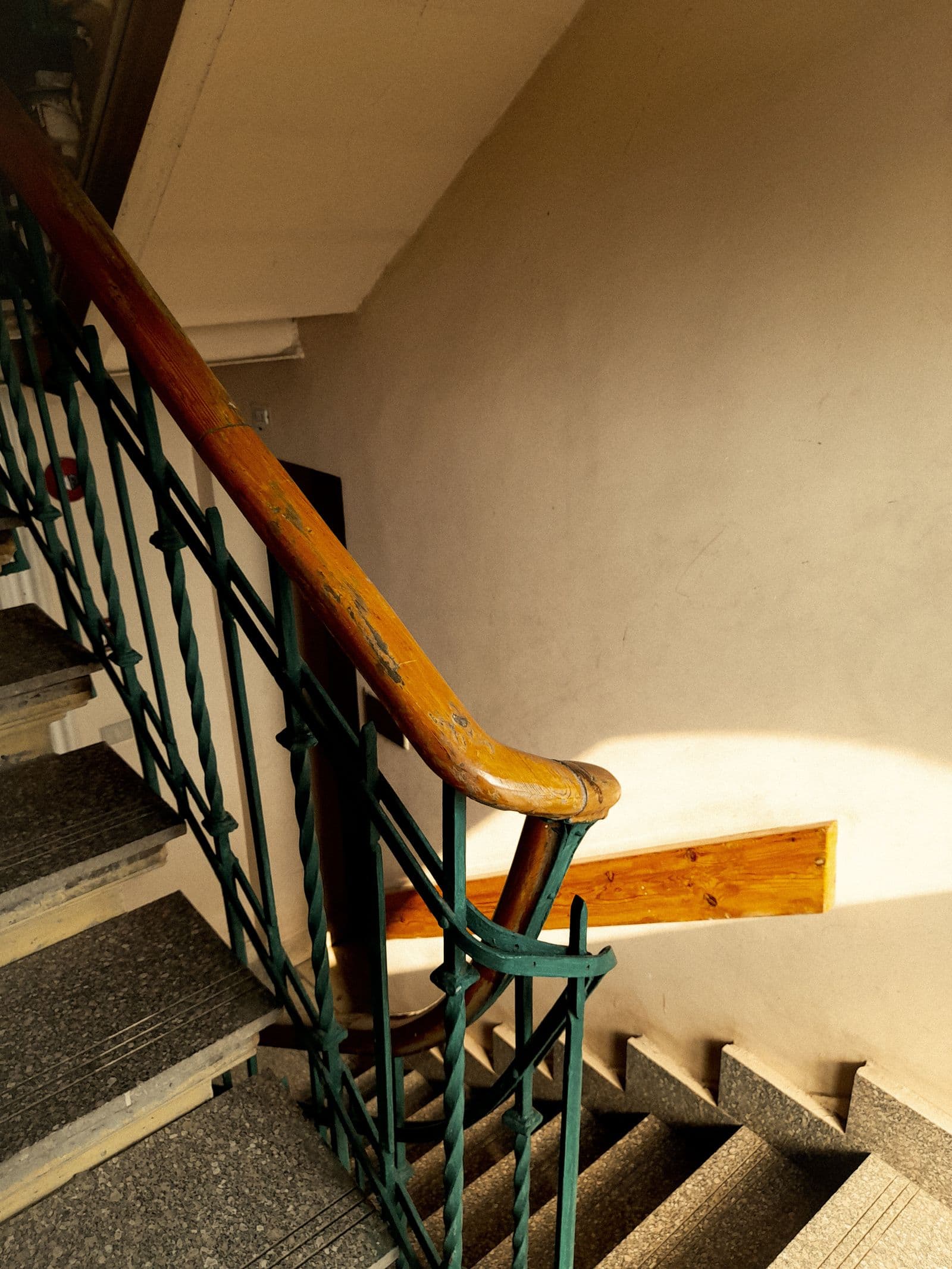 Escalier d'immeuble à rampe bois et marches granito