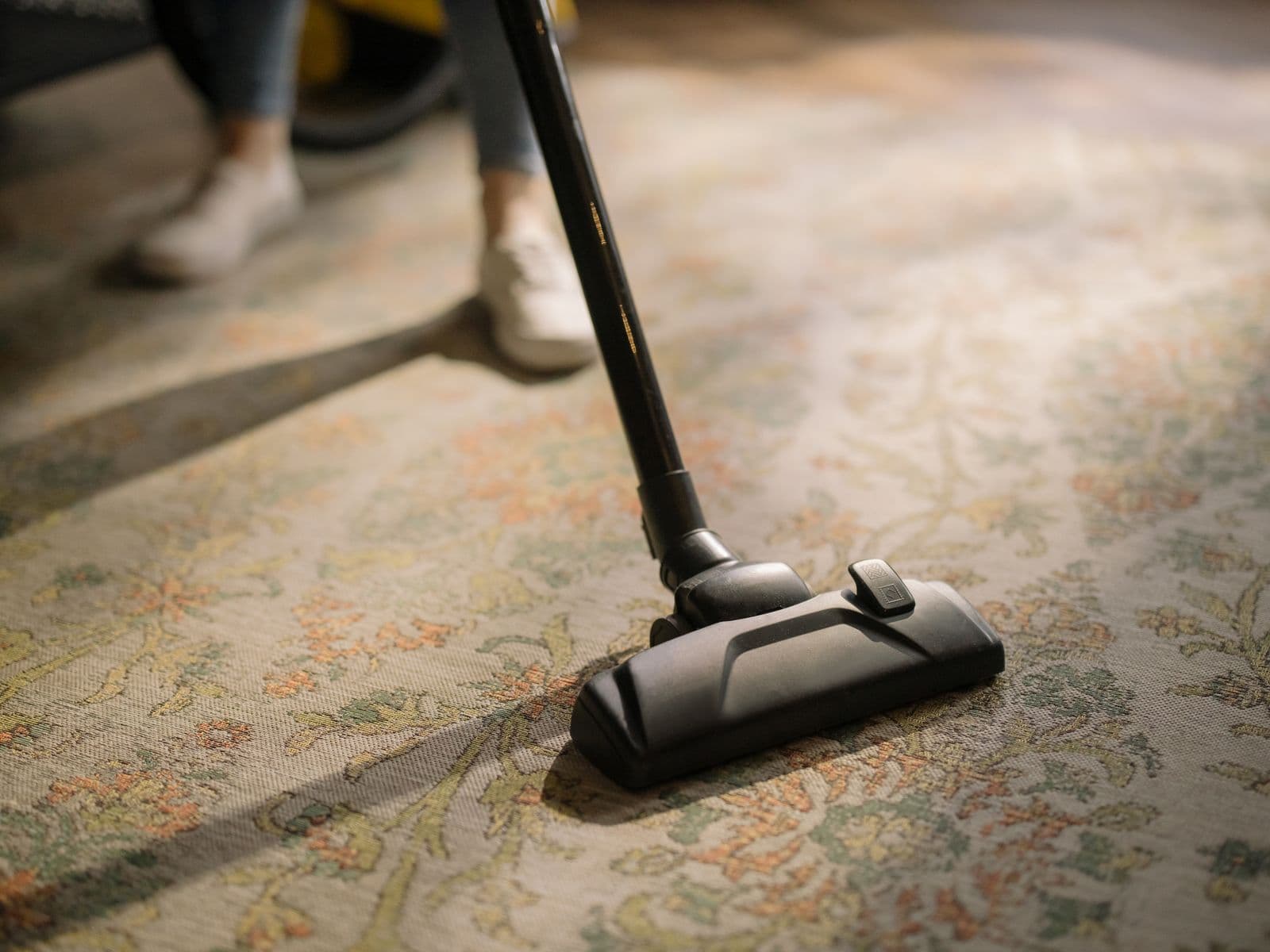 Aspirateur passé lentement sur un tapis à motifs