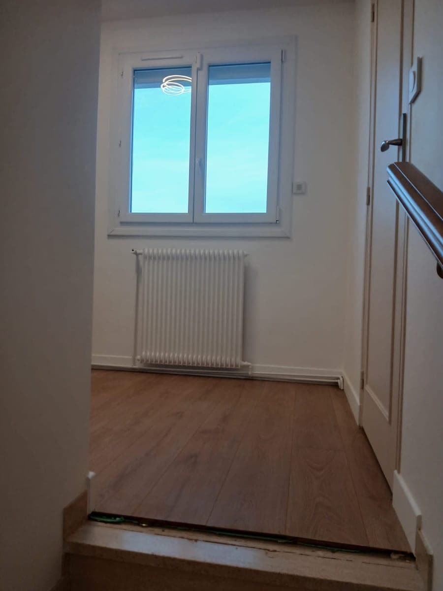 Chambre à l'étage, parquet clair, radiateur blanc sous la fenêtre