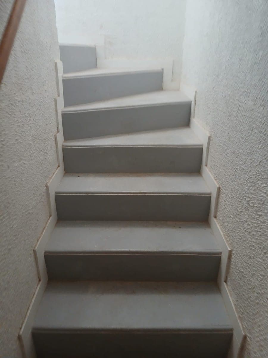 Escalier de sous-sol aux marches grises propres entre deux murs blancs