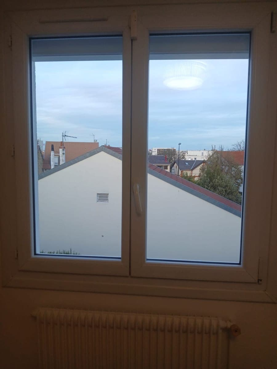 Fenêtre double vantail aux vitres nettes, vue dégagée sur les toits