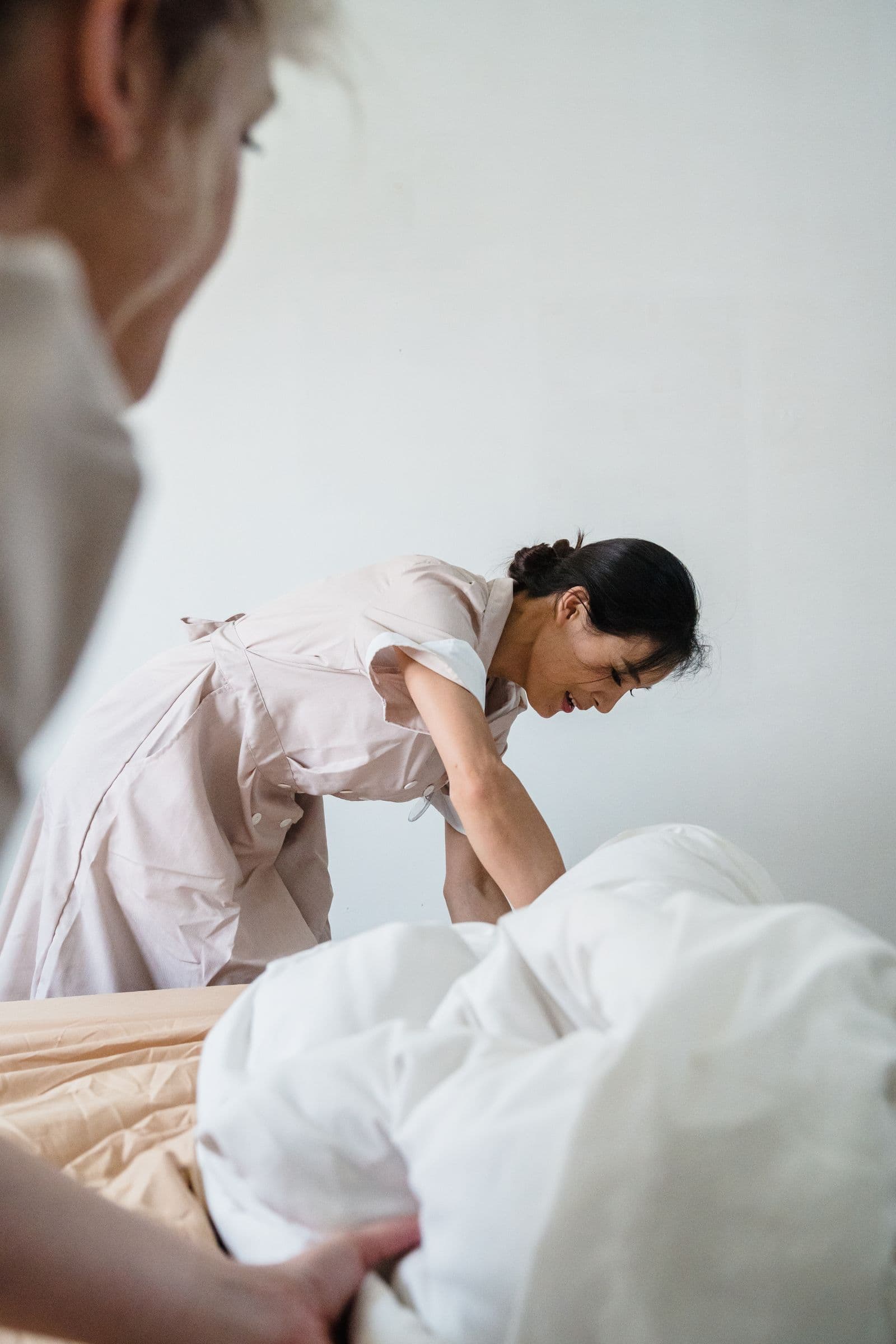 Femme de chambre bordant un lit aux draps blancs