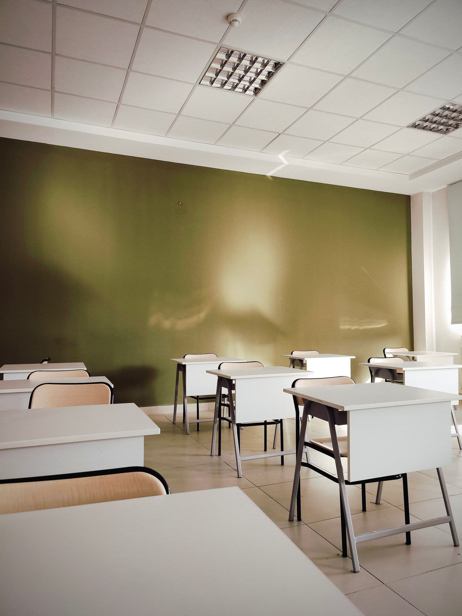 Salle de classe vide aux tables blanches alignées