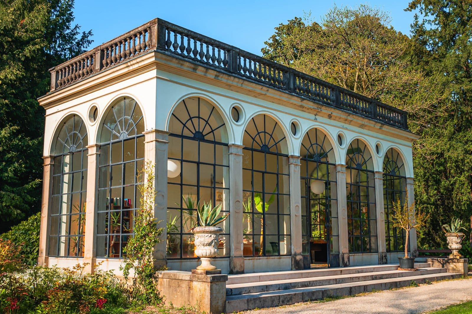Orangerie vitrée baignée de soleil dans un jardin
